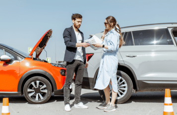 2 people exchanging insurance information after getting into a car accident.