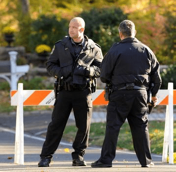 police officers waiting for a hazmat cleanup crew to arrive after a car accident.